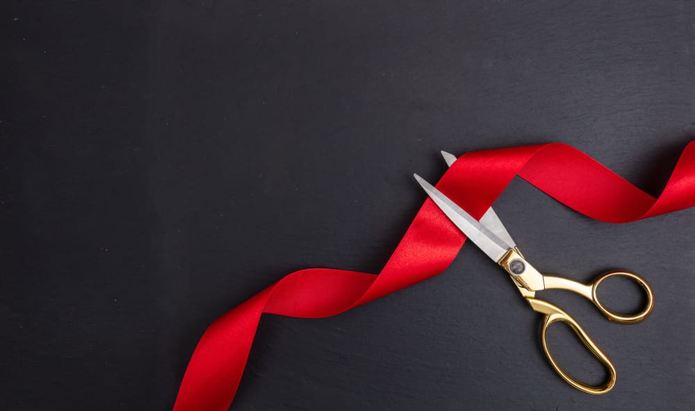 Gold scissors cutting red silk ribbon for the grand opening of NiteOwl Urgent Care Ooltewah.